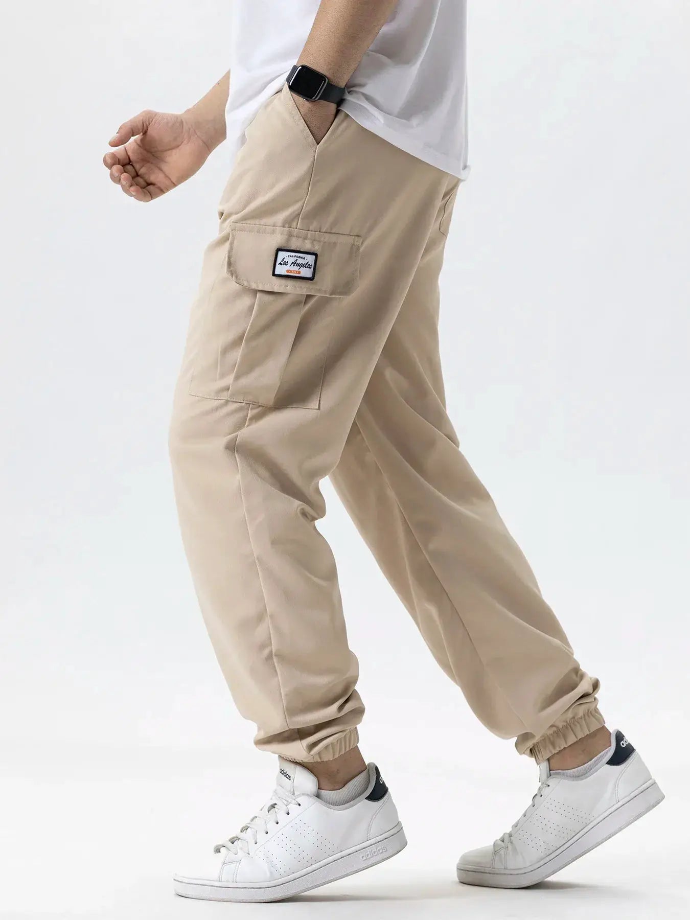 Men's beige cargo joggers with side cargo pocket and Los Angeles patch; elastic cuffs.