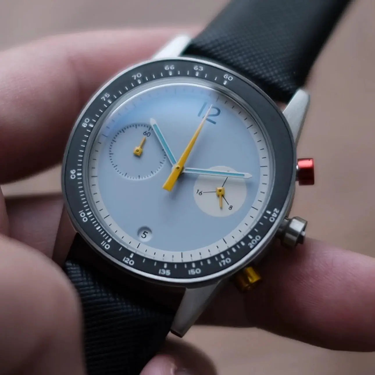 Men's quartz watch from Simples Market with light blue dial, yellow hands, and black fabric strap.