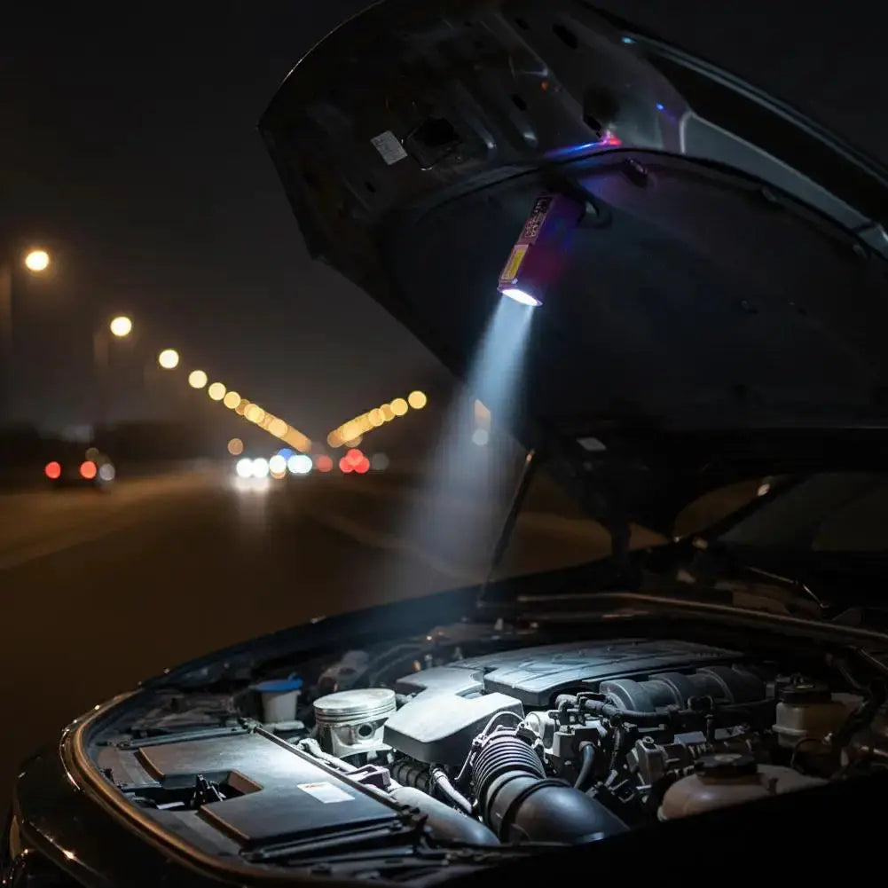 Simples Market mini COB LED keychain flashlight, purple, hanging from car hood to light the engine bay.