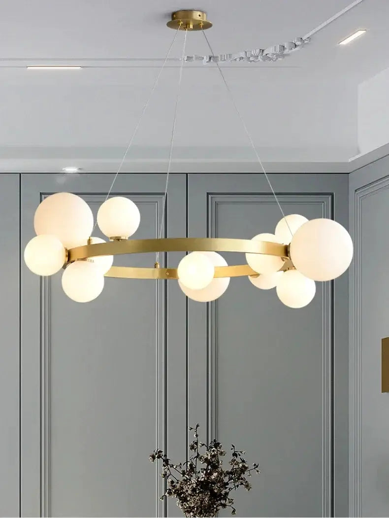 Simple Chandeliers Indoor Lighting by Simples Market; gold circular ring chandelier with frosted globe bulbs hanging.