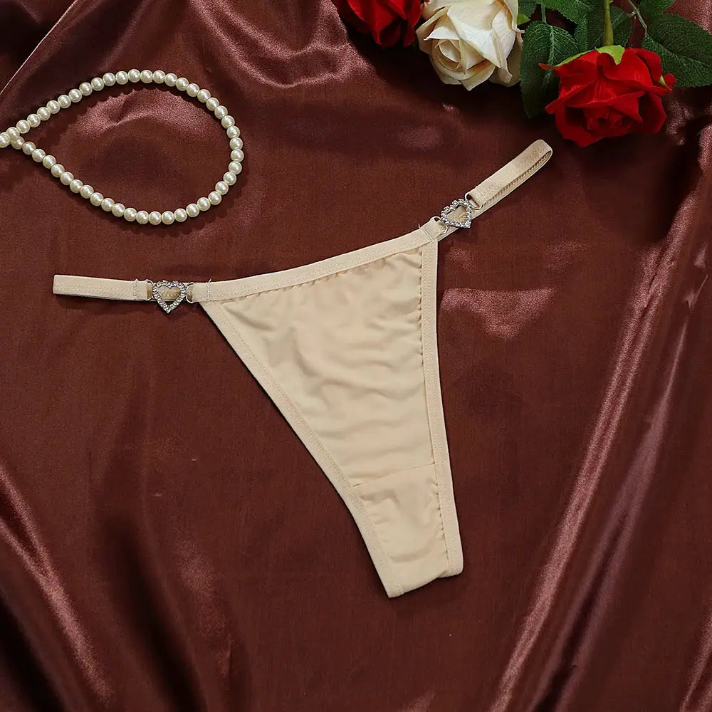 Beige cotton thong with heart-embellished side straps and subtle rhinestone accents; low-rise G-string style for women.