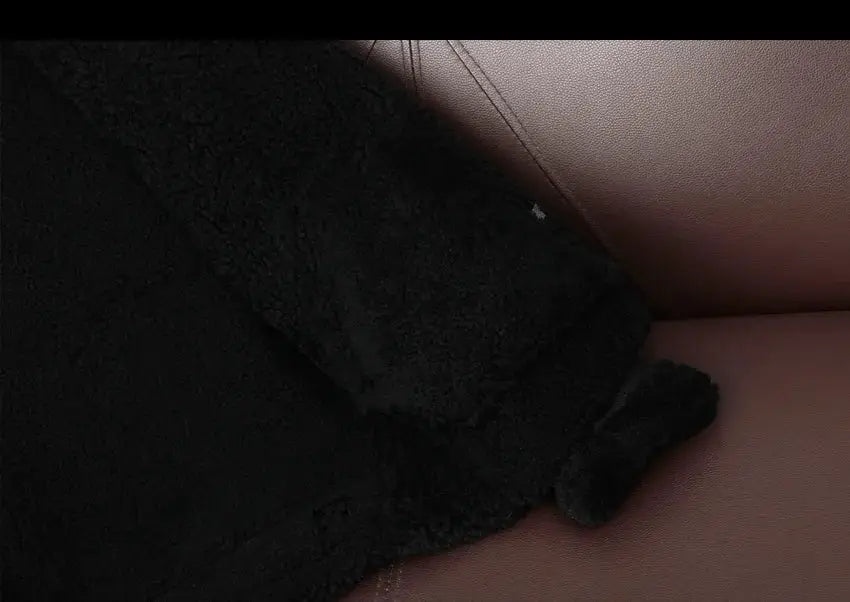 Black shearling fur jacket cuff close-up showing thick sheep wool texture
