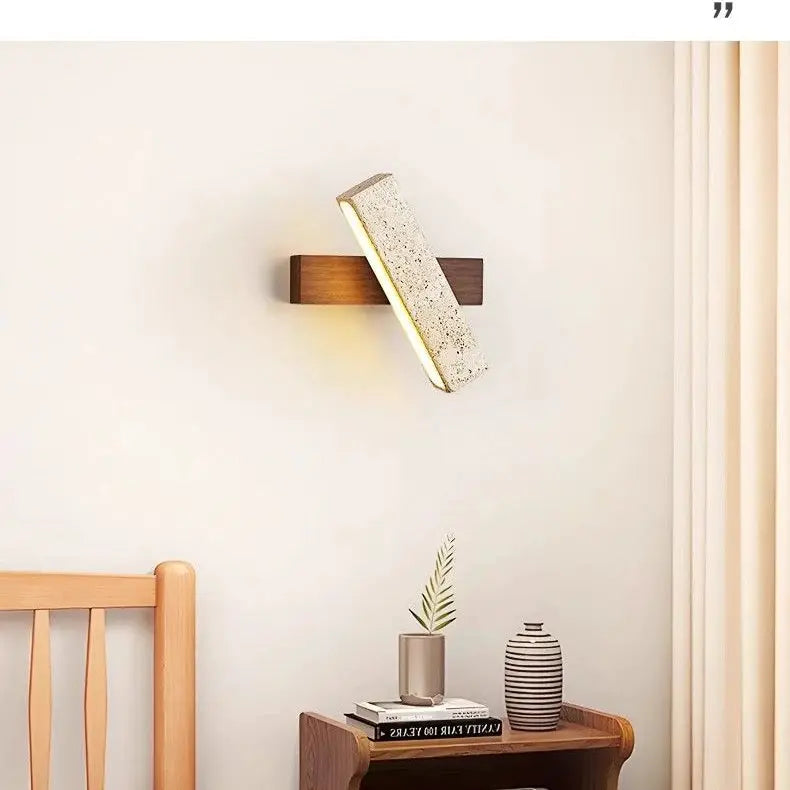 Natural stone wall lamp sconce with rectangular beige stone on a dark wood backplate, emitting warm light.