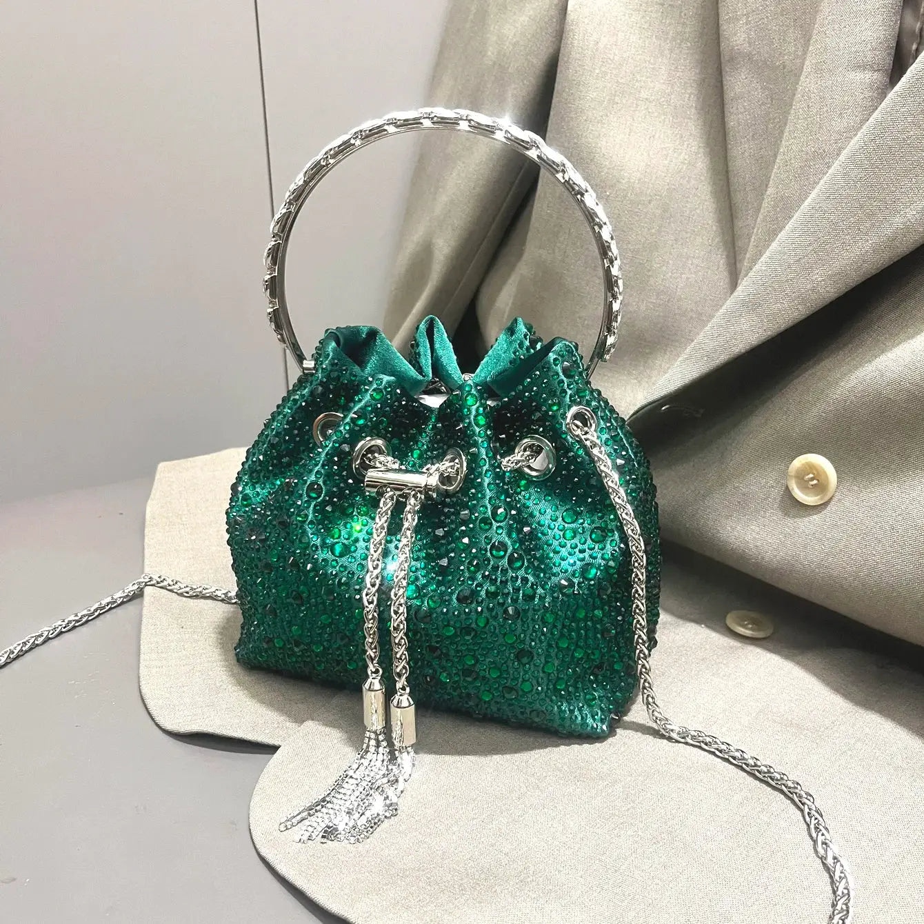 Emerald green rhinestone evening clutch with silver hoop handle and tassel fringe.