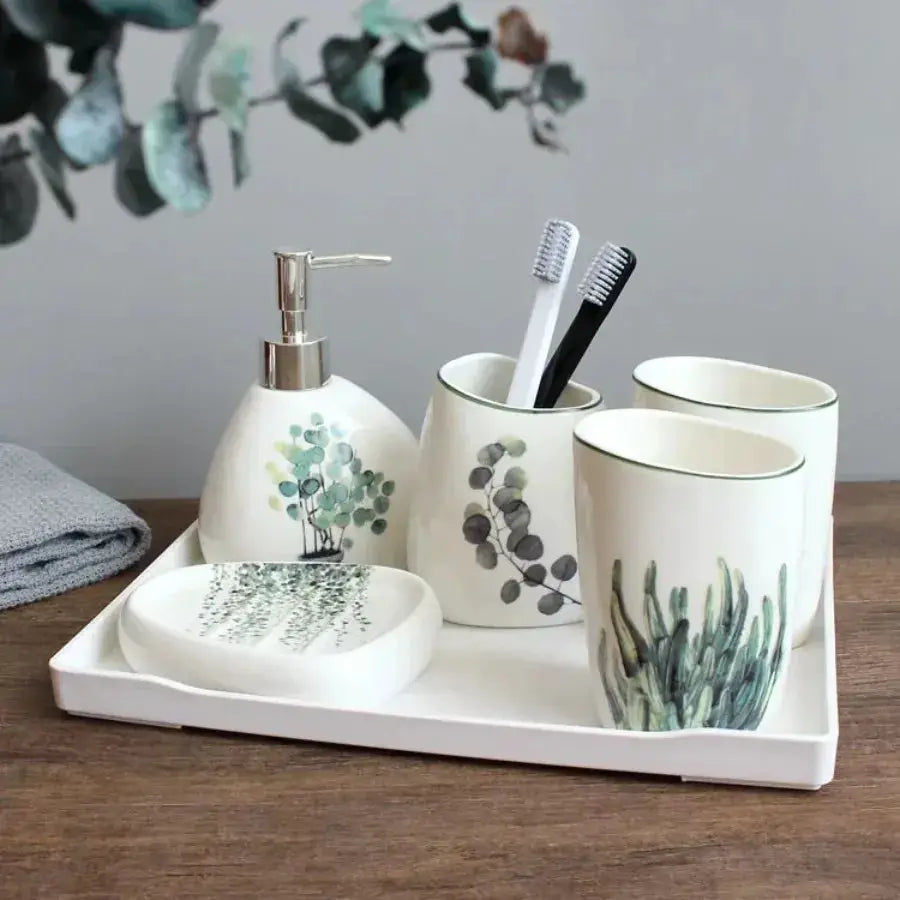 Simples Market white ceramic bathroom set on a tray; soap dispenser, mouthwash cup, toothbrush holder, botanical leaf designs.