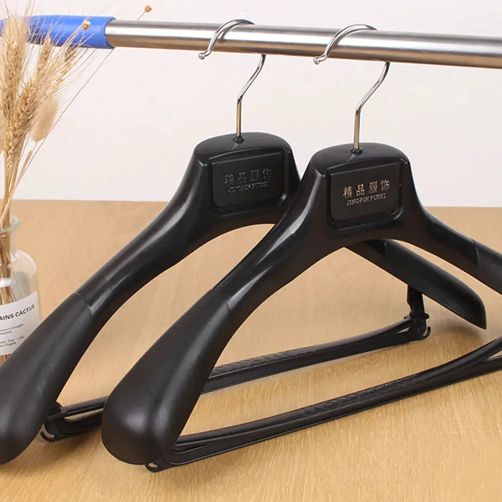 Simples Market 5-pack wide-shoulder black plastic clothes hangers with metal hooks for wardrobe organization.