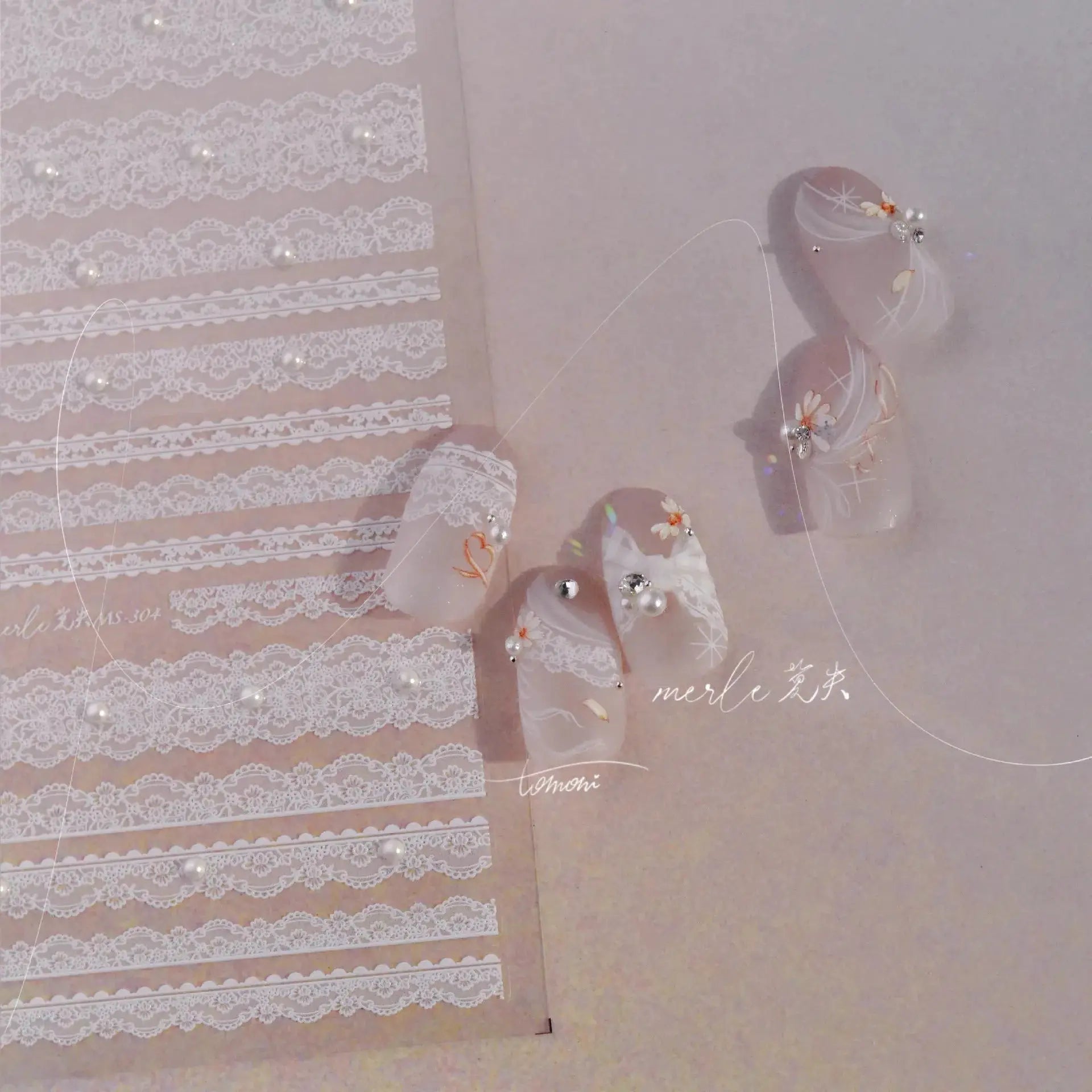 Nail art stickers by Simples Market—white lattice lace strips with pearl accents on pink floral nails