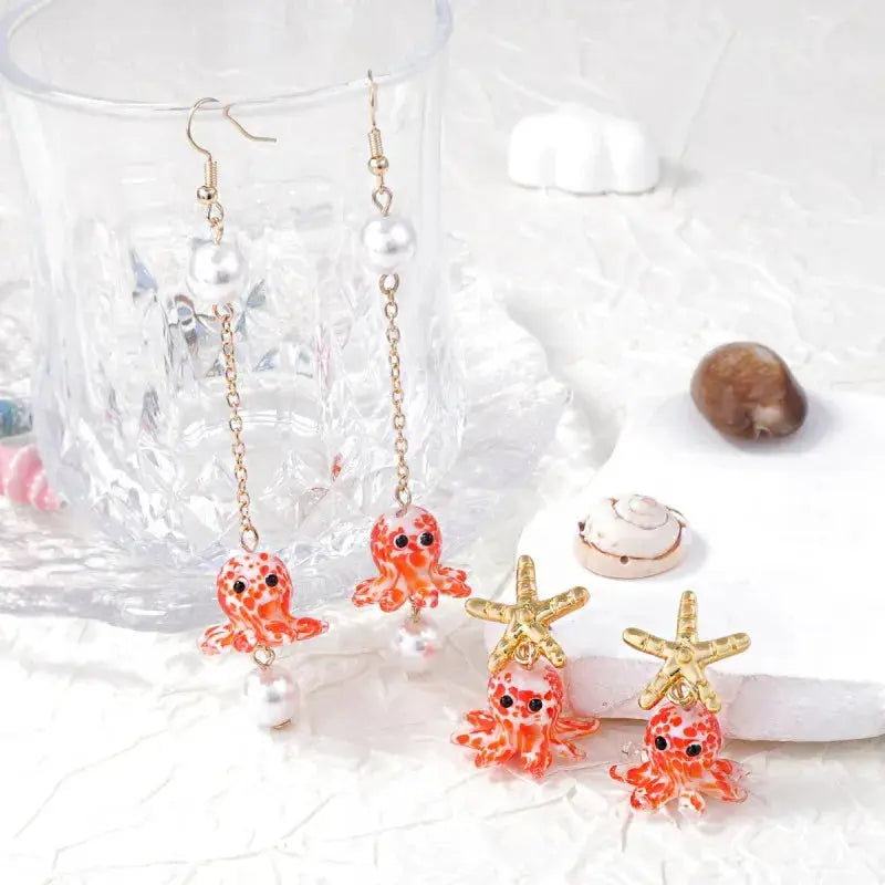 Simples Market octopus earrings set; two pairs, orange glass octopuses with pearl drops on gold chains; starfish-top