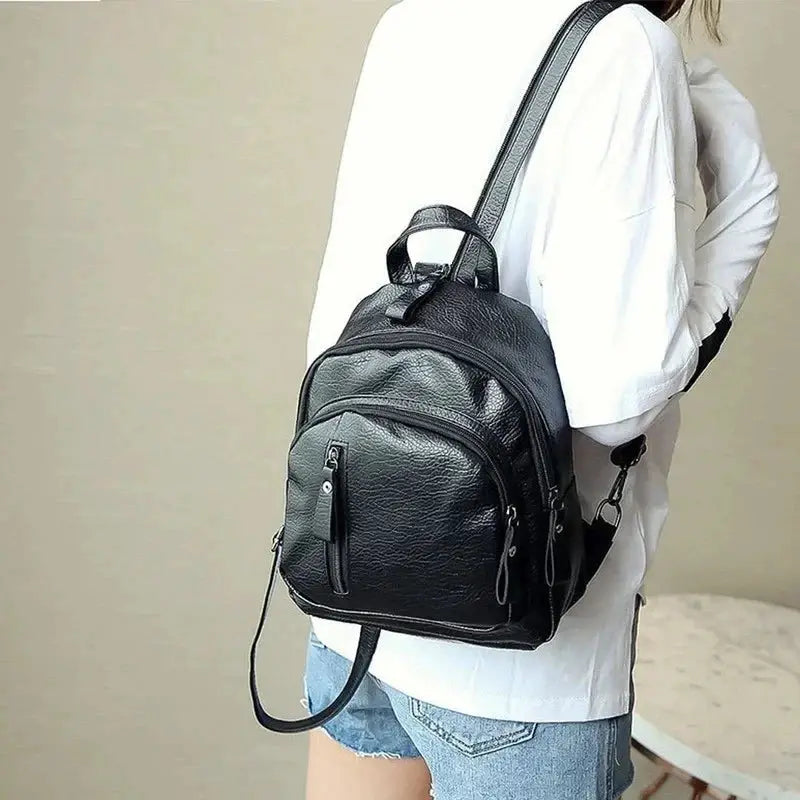 Mini black faux leather backpack for men with front pockets, top handle, and adjustable shoulder straps