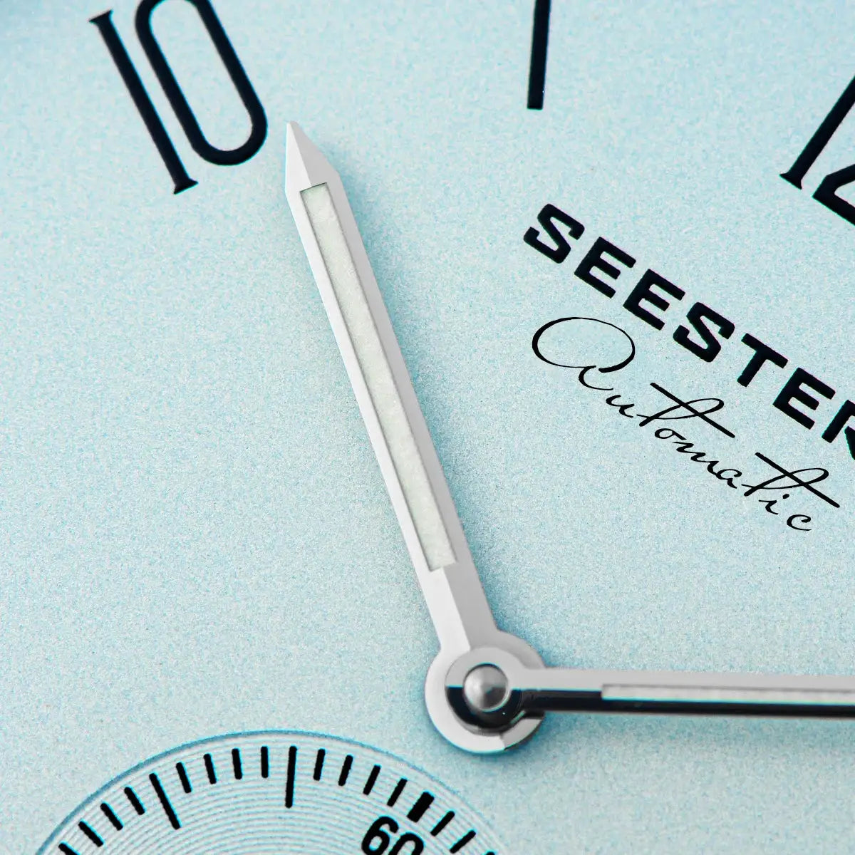 Men's SEESTER wristwatch dial close-up with silver hands on a light blue background