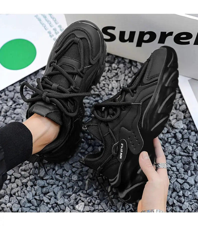Pair of men's black sneakers with thick soles; breathable mesh, casual outdoor wear; Supreme box in background.