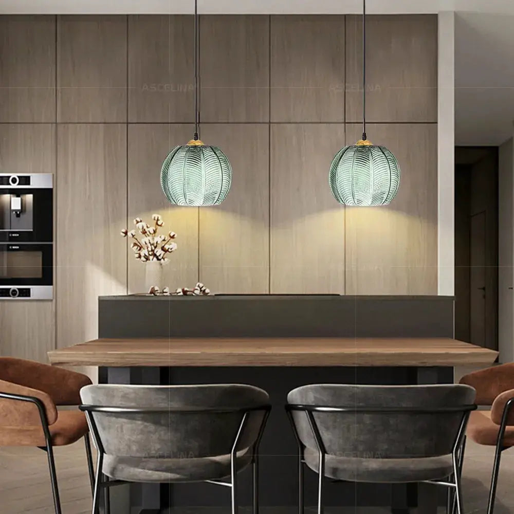 Nordic glass pendant lights with green leaf-pattern shades, 2 fixtures over a wooden dining table.