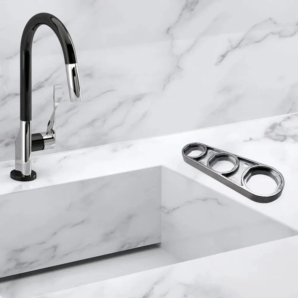 Simples Market 6-in-1 faucet wrench tool, metal with black accents, displayed beside a chrome faucet on a marble countertop.