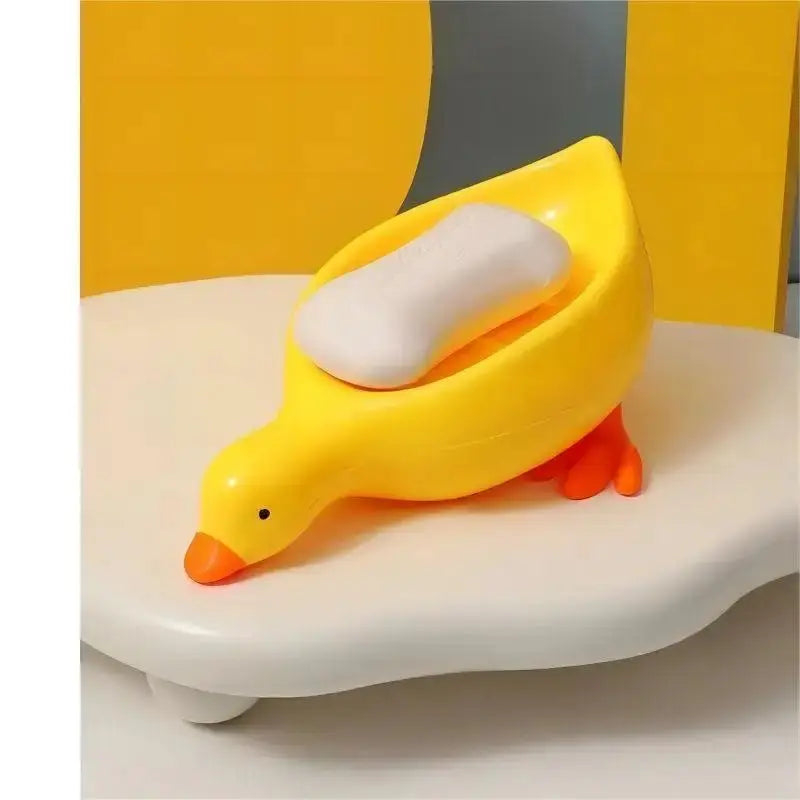 Duck-shaped yellow self-draining soap rack with white soap on a white bathroom sink