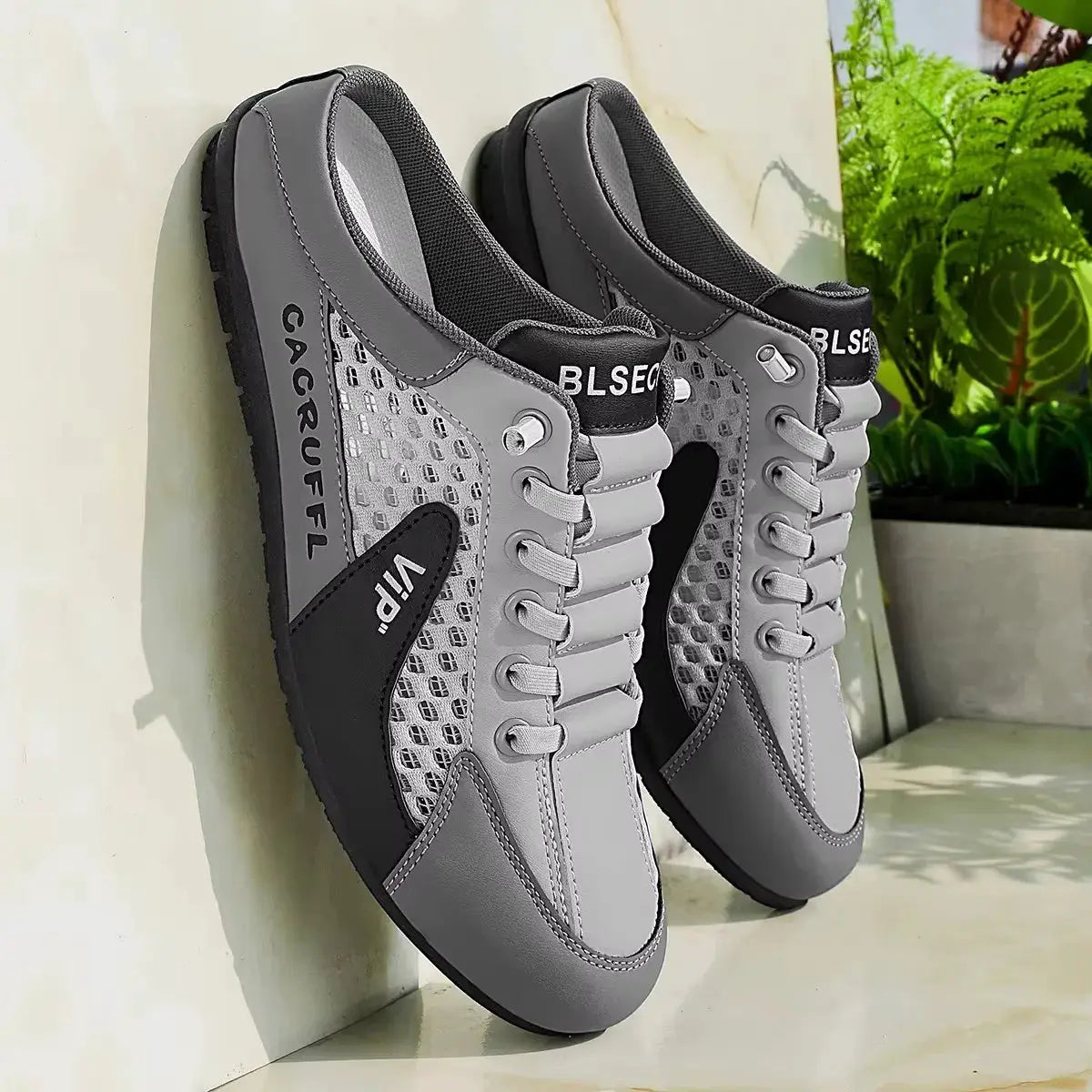 Pair of gray men's casual slip-ons with mesh panels and lace accents.
