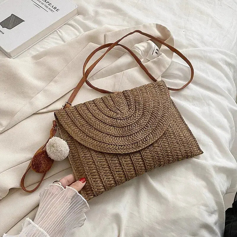 Brown handmade straw crossbody bag with envelope flap and pompom charm