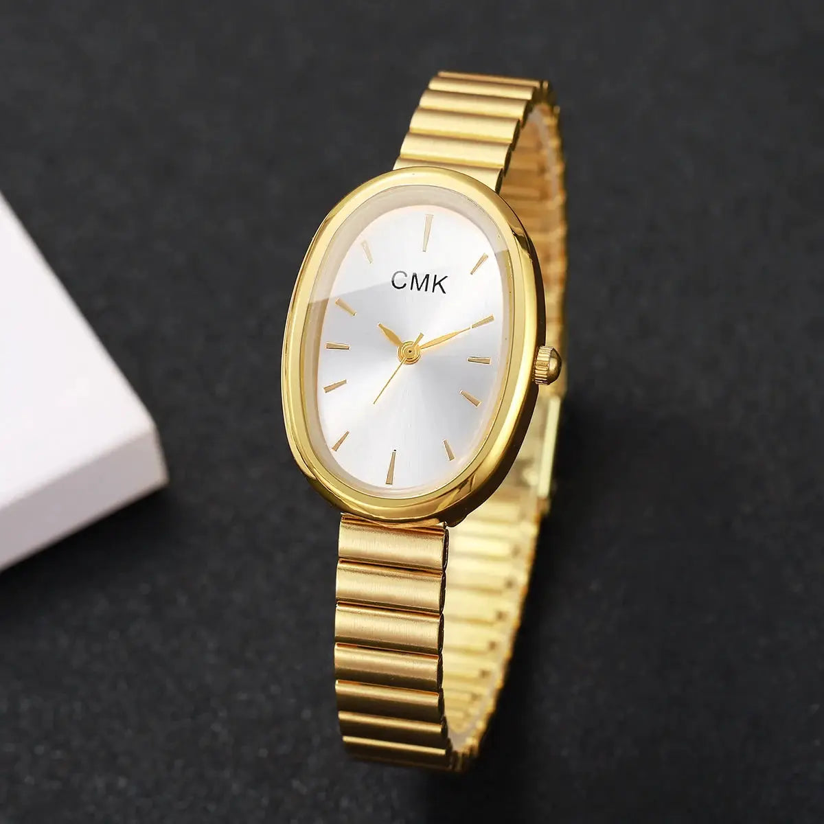 Women's gold-tone oval-dial wristwatch with a slim metal bracelet; CMK on silver dial.