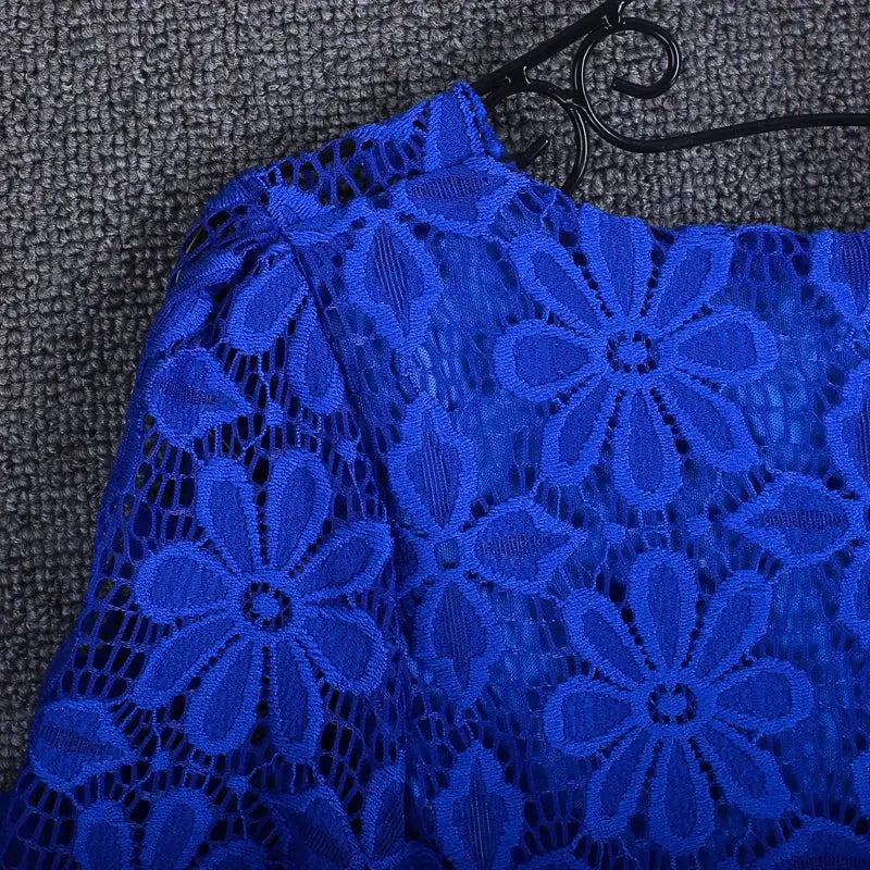 Women's royal blue lace blouse on hanger with floral cutout pattern.