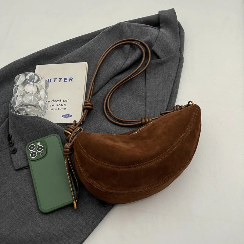 Simples Market brown faux suede shoulder bag with long strap, crossbody style beside a gray blazer
