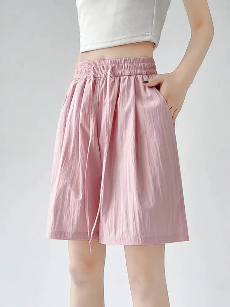 Pink high-waisted women's shorts with elastic waistband, drawstring, and two pockets.