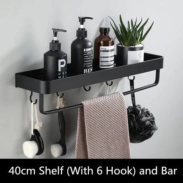 Wall-mounted bathroom shelf in black aluminum, 40cm with six hooks and towel bar, holds bottles and a plant.