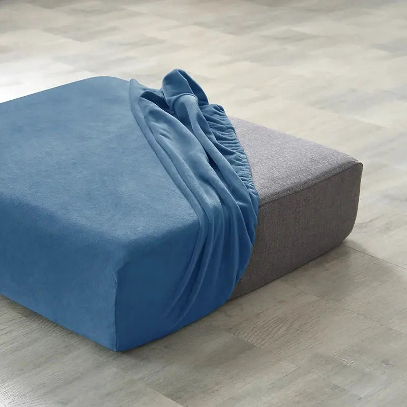 Blue plush sofa slipcover with elastic anti-slip edge on a gray ottoman.