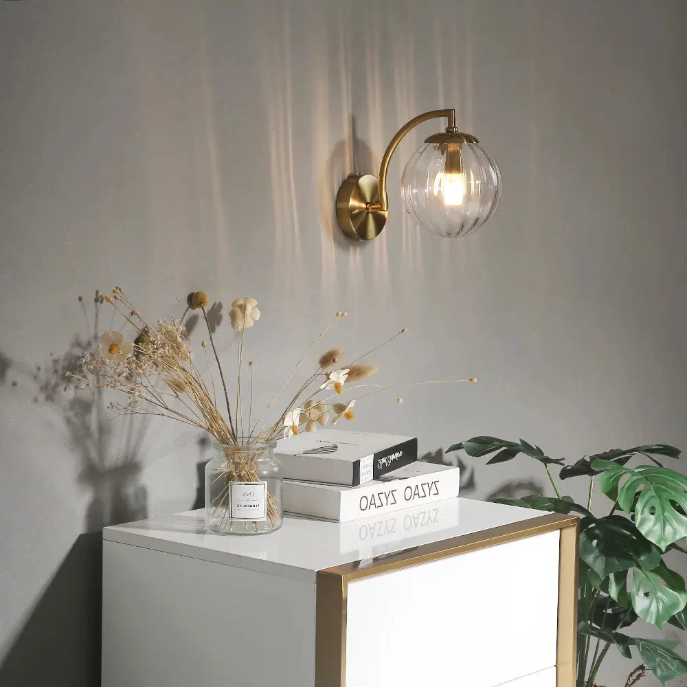 Modern LED wall lamp by Simples Market; brass arc sconce with clear glass globe for bedroom