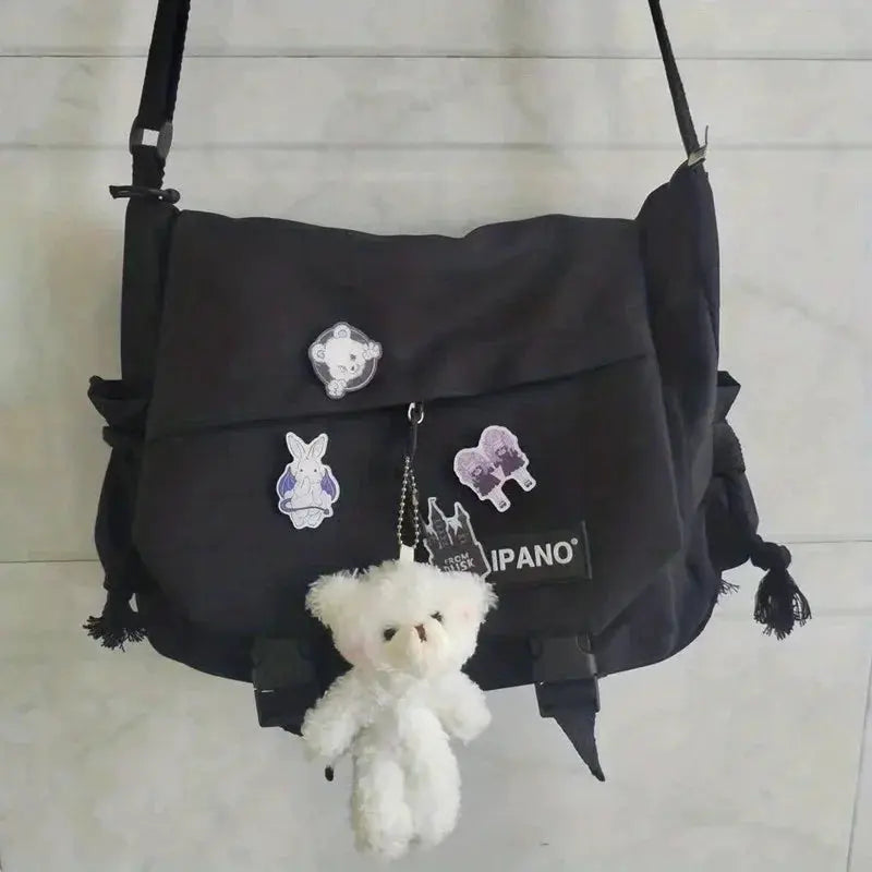 Men's black nylon crossbody bag with front flap, large capacity, patches, and a white plush teddy keychain