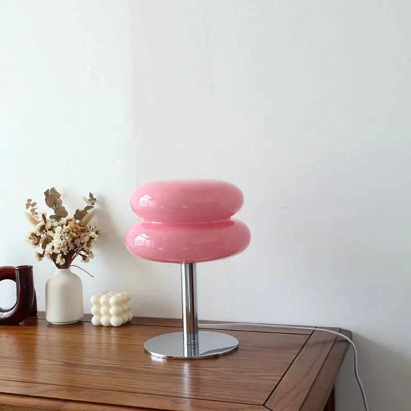 Macaron glass table lamp in pink with chrome stem on a wooden desk