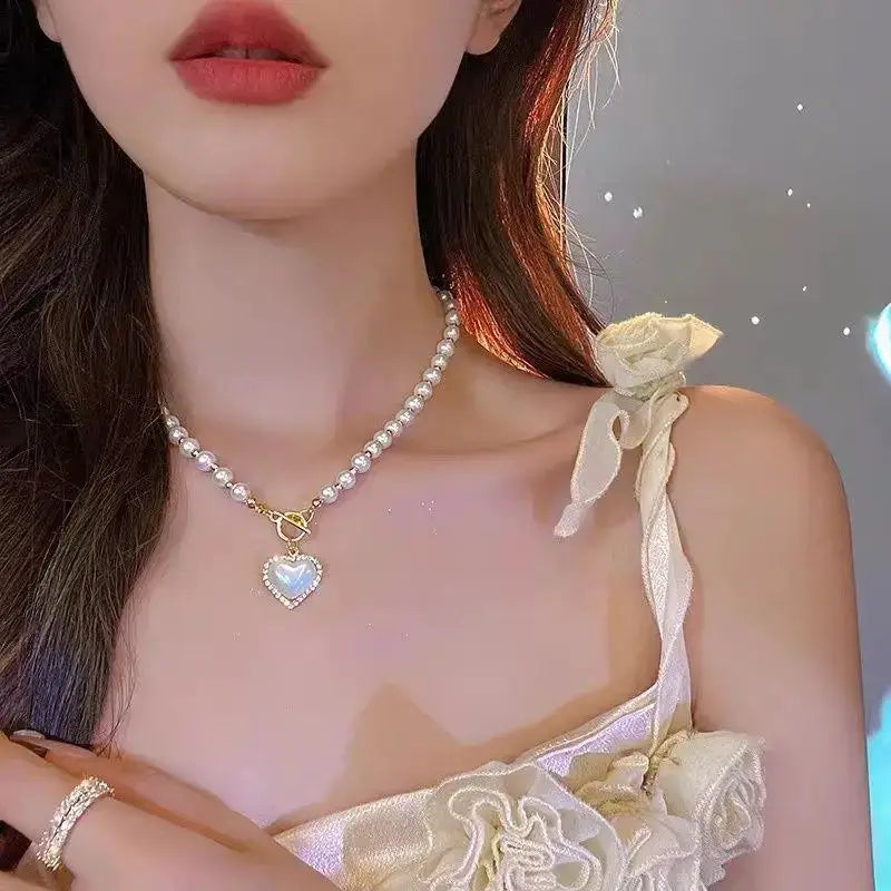 Gold-tone pearl choker necklace with a heart-shaped iridescent pendant