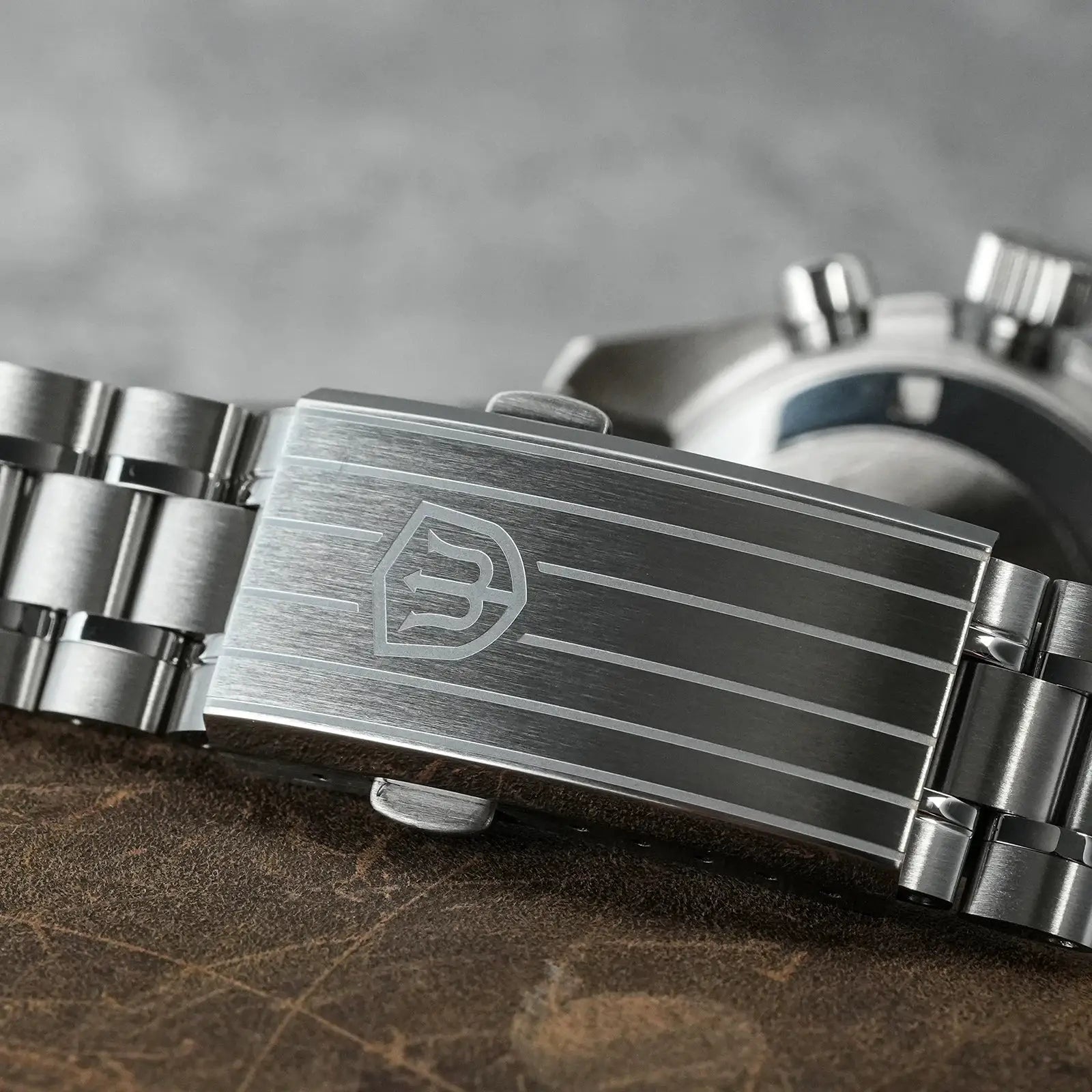 Stainless steel watch bracelet with brushed links and shield logo clasp