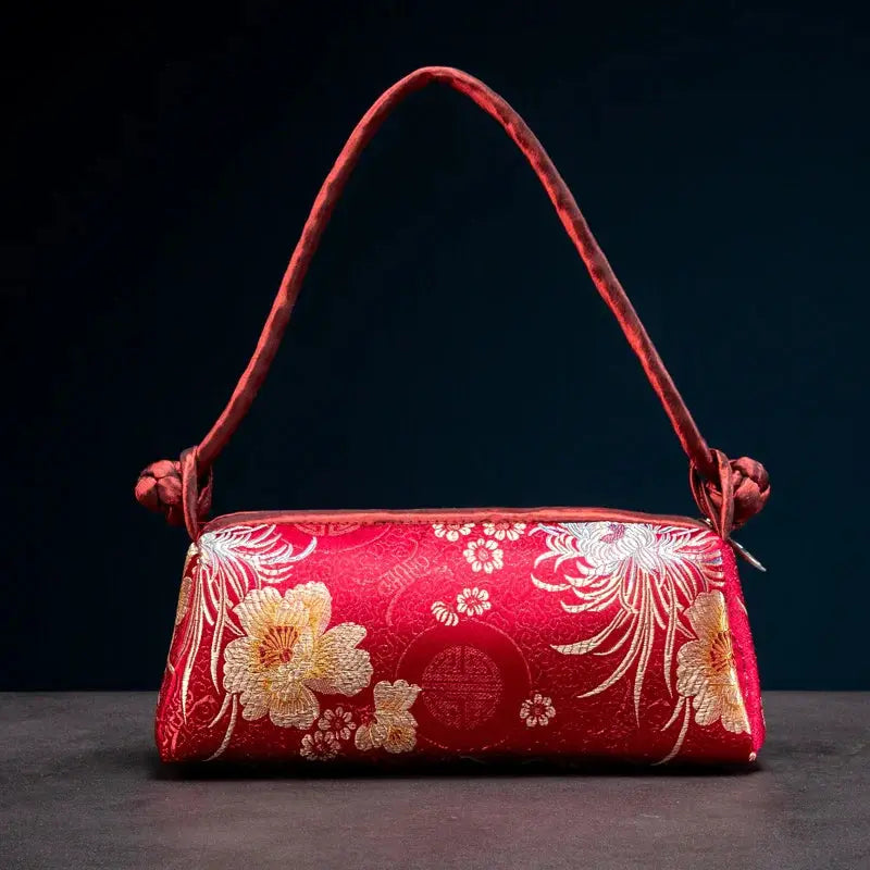 Red silk-embroidered shoulder bag by Simples Market with a gold floral motif, compact satin purse