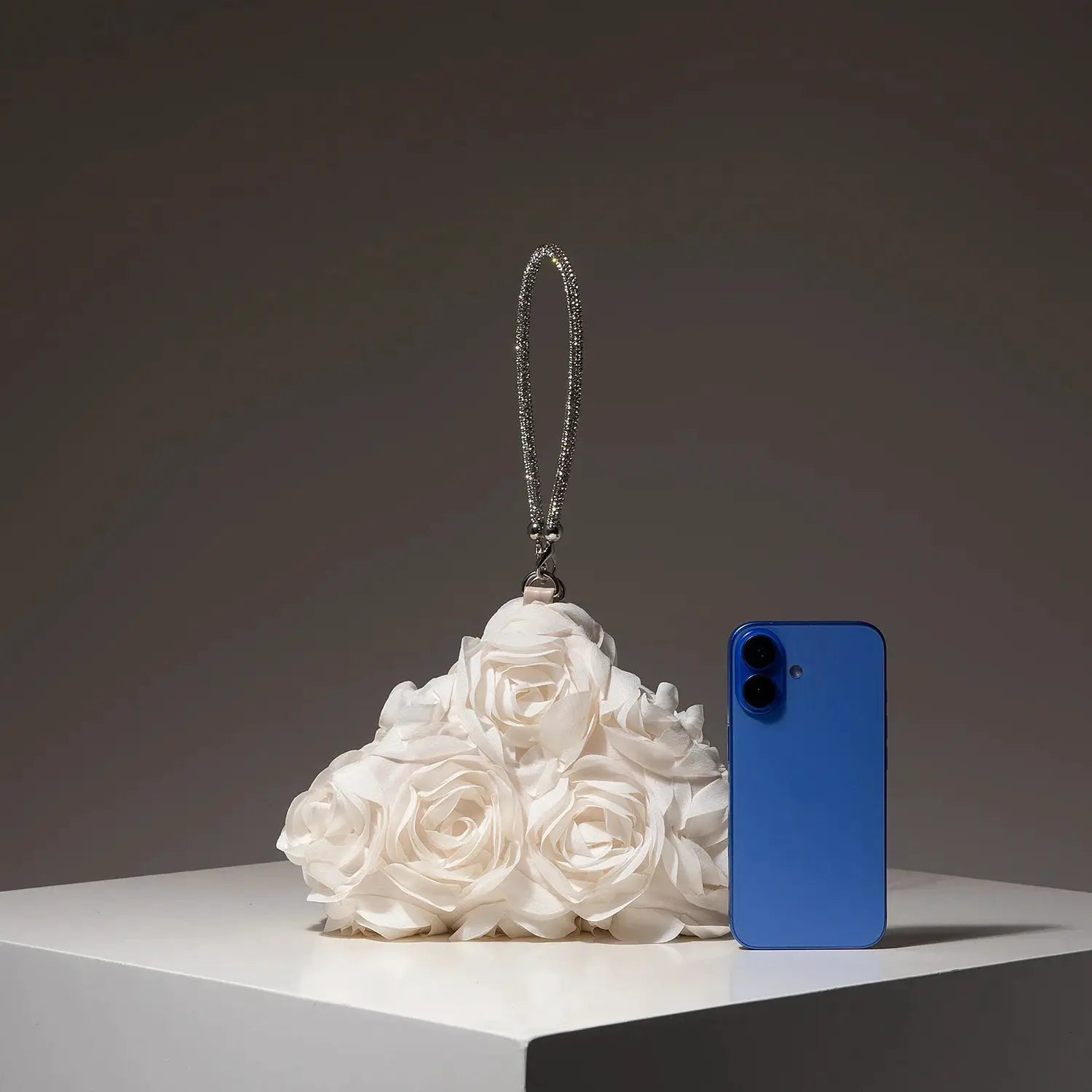 Mini Purse by Simples Market; floral party bag charm with rhinestone strap beside white roses and a blue phone.