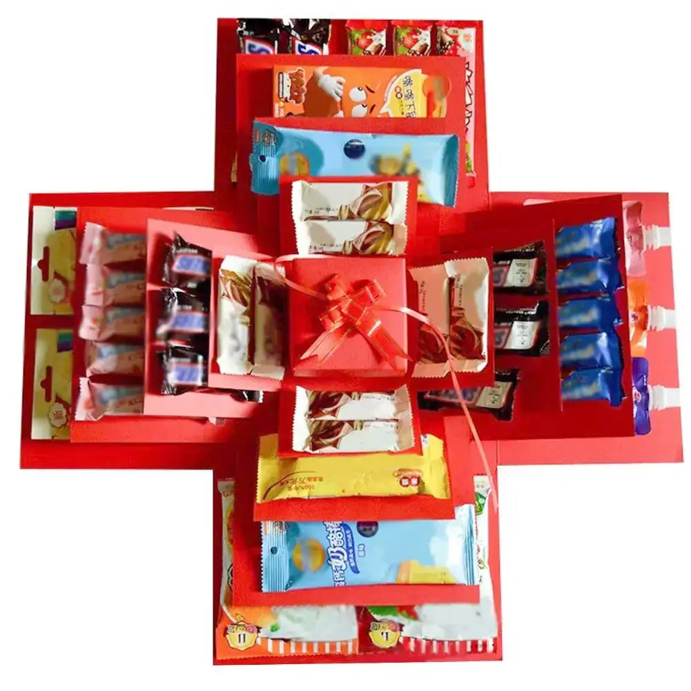 Red DIY explosion box gift with layered panels, ribbon, and assorted candy wrappers inside