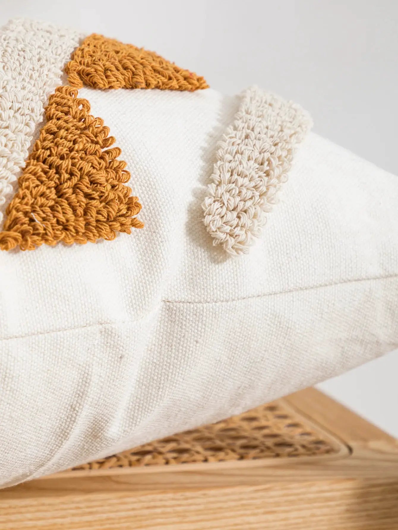 Pillow cover by Simples Market with multi-color geometric boho loop velvet trim on beige sofa.