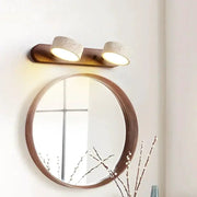 Round wooden-framed mirror with twin concrete-textured LED wall lamps on a wood backplate