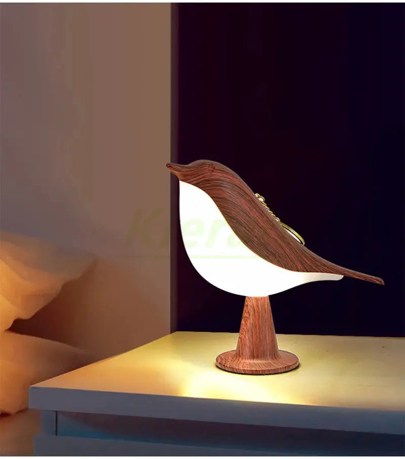 Magpie-shaped LED desk lamp with wood grain body and white belly on a round wooden base, warm bedside light