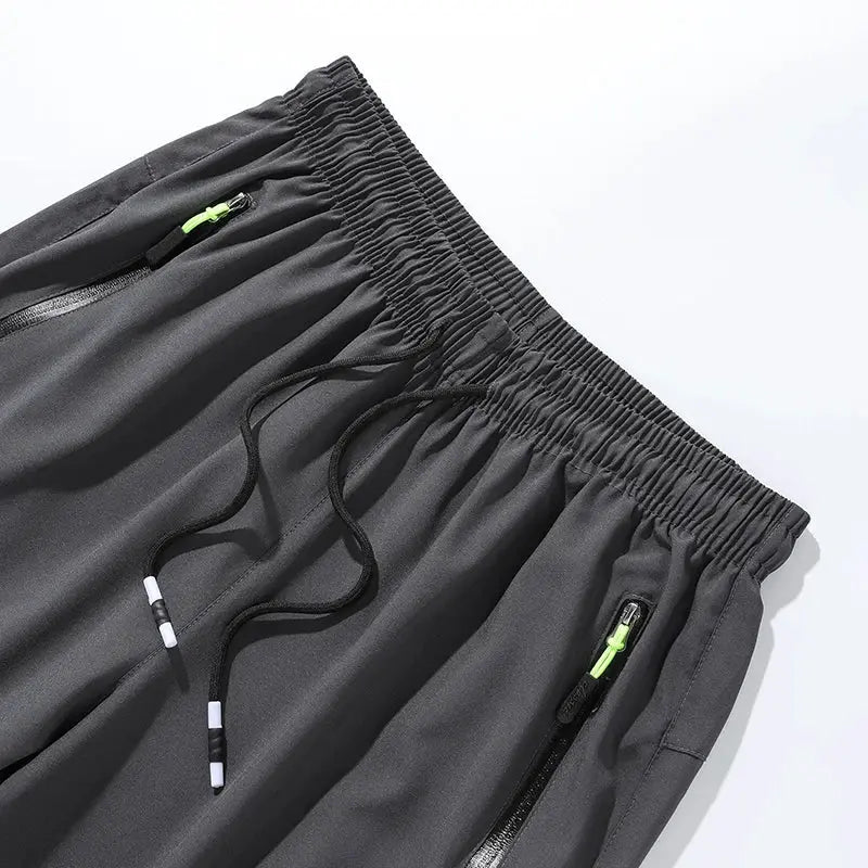 Breathable men's gray quick-dry jogger pants with elastic waist, drawstring, and neon-green zipper pockets
