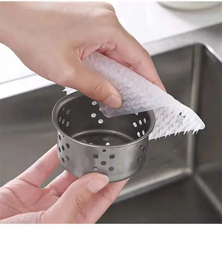 White silicone dish scrubber crevice brush used to clean a perforated metal cup in the kitchen
