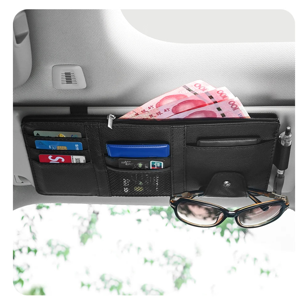 Car sun visor organizer in black leather with zipper pocket, card slots, sunglasses clip, and pen holder.