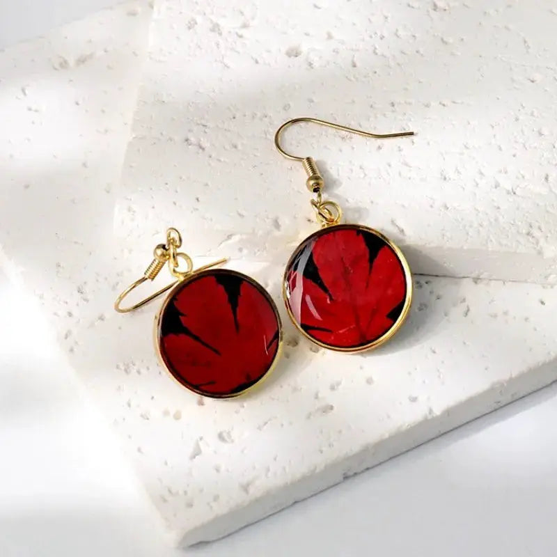 Round epoxy resin earrings with red pressed flower design, gold-tone frames and hooks