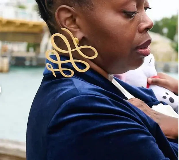 Large gold-tone squiggle dangle earrings, 1 pair, worn by a woman