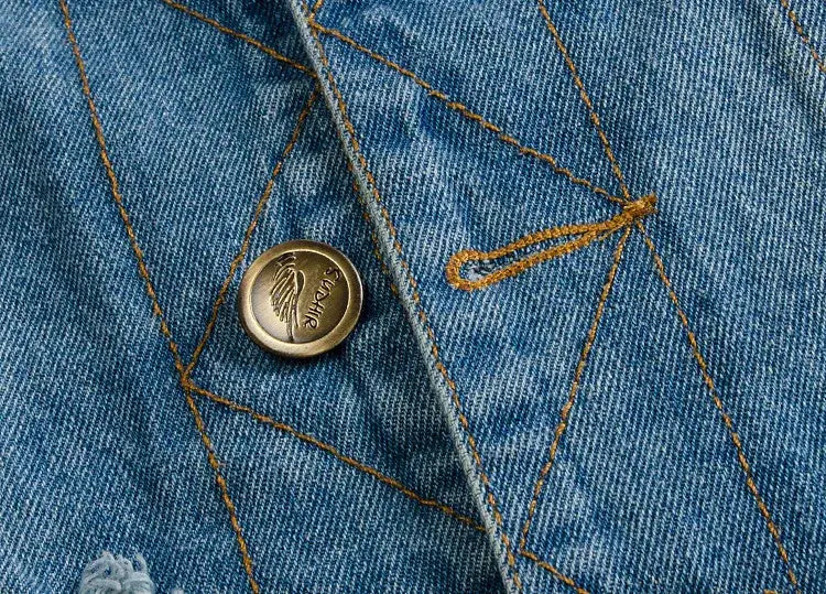Men's light blue denim vest close-up showing orange contrast stitching, visible seams, and a metal button detail.