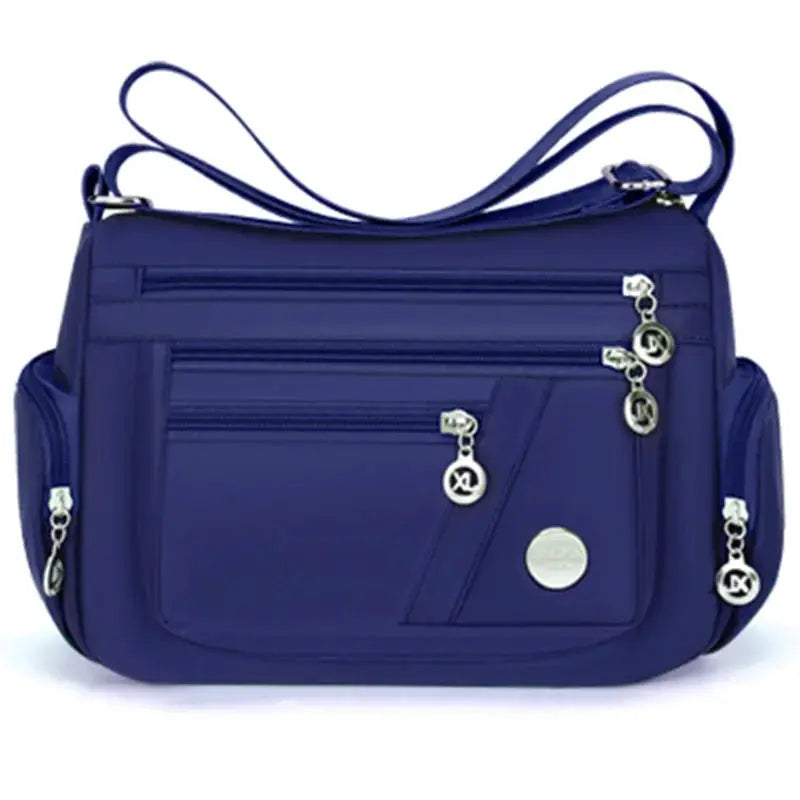 Crossbody handbag by Simples Market in blue nylon with multiple zip pockets and adjustable strap.