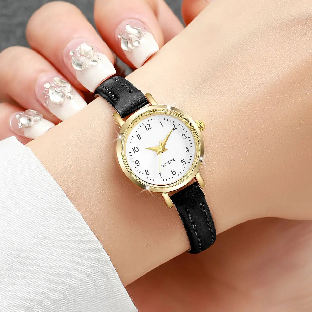 Women’s fashion quartz watch with gold-tone case, black leather strap and white dial.