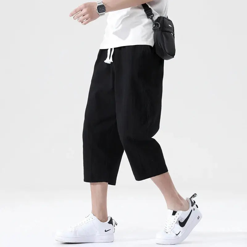 Men's summer linen shorts, black cropped straight-leg with white drawstring, paired with white Nike sneakers