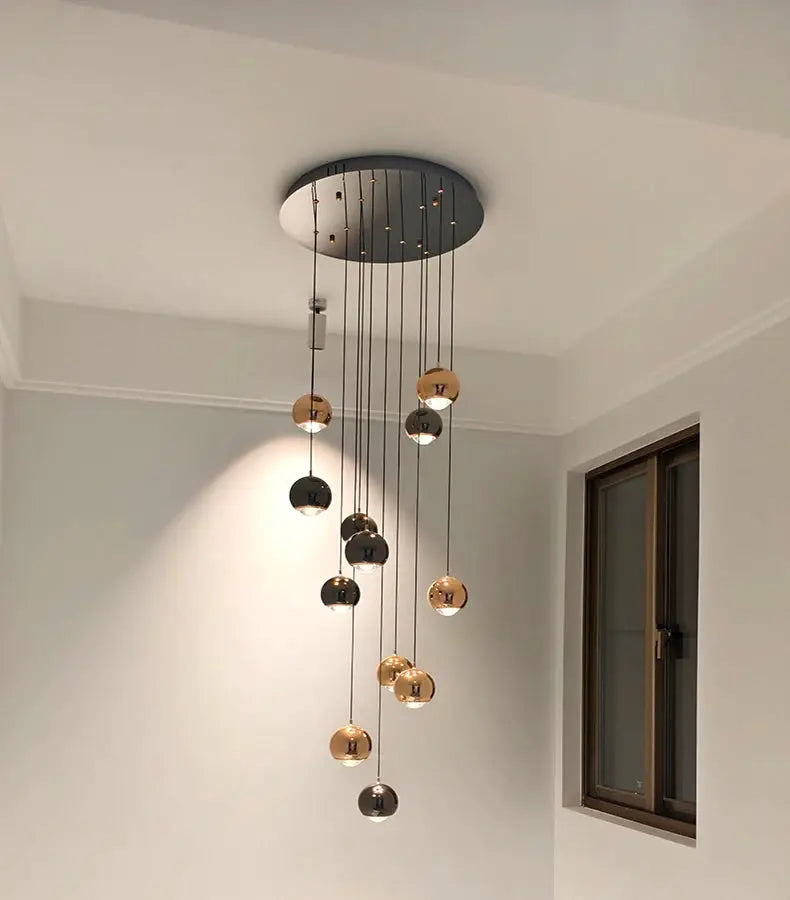 Modern pendant light fixture with multiple hanging metallic LED spheres in gold and chrome, ceiling mount