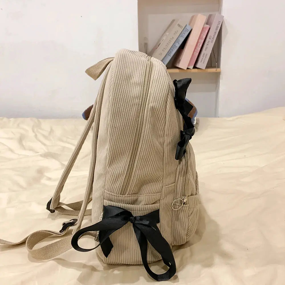 Corduroy beige backpack with black ribbon bows, adjustable straps