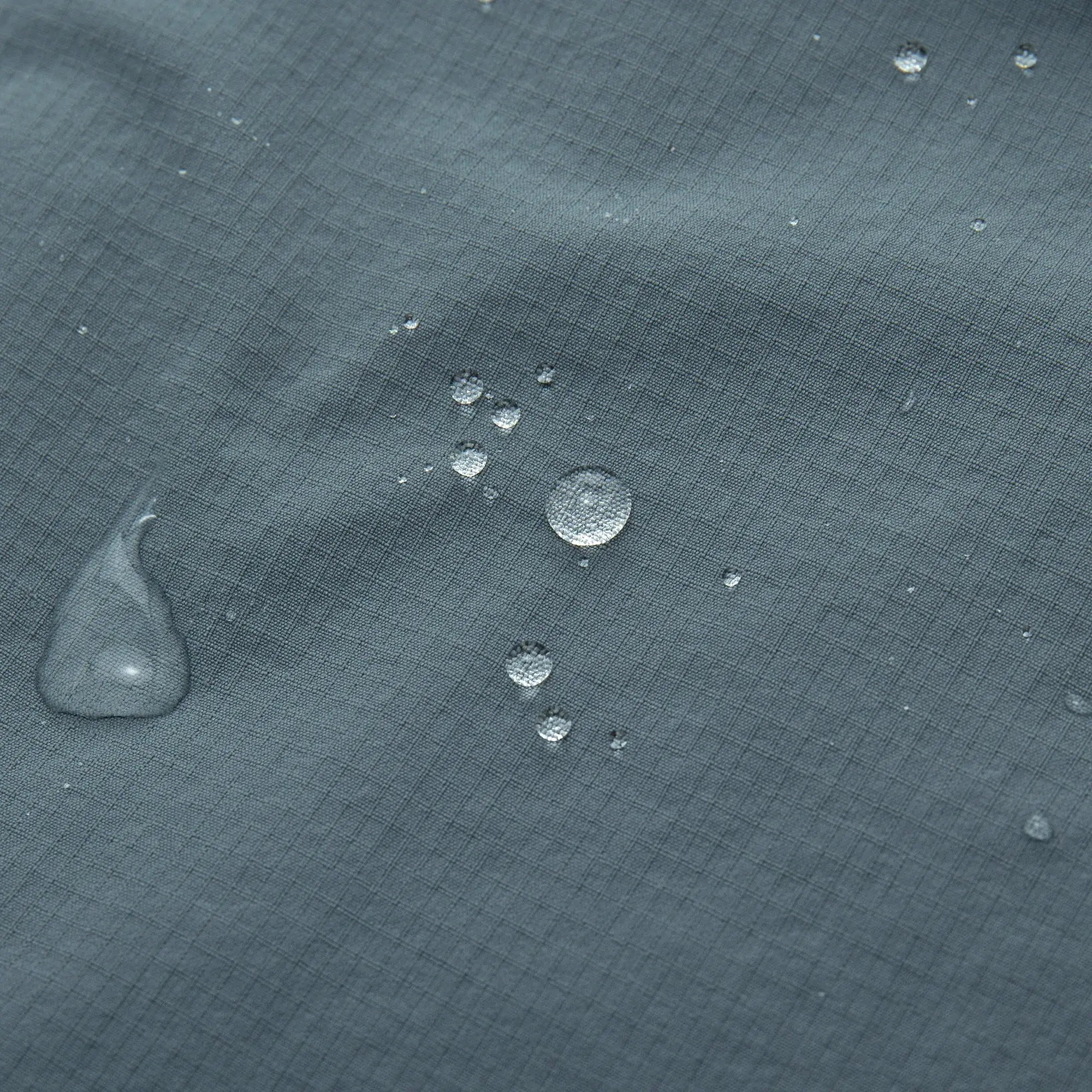 YKYWBIKE men's cycling windbreaker vest fabric close-up in blue-gray with water droplets.