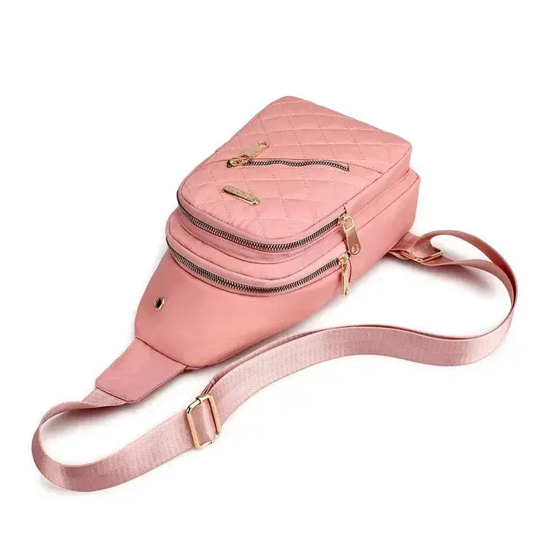 Pink quilted crossbody bag with gold zippers, multiple compartments and an adjustable strap.